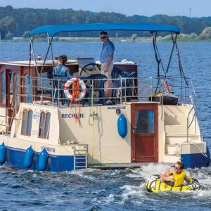 eone Kormoran fährt über einen See und zieht einen Jungen auf einer Badeinsel hinterher