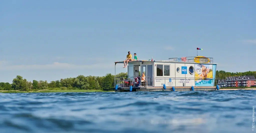 ein Febomobil mit 4 Personen an Bord vor dem Hafendorf Müritz