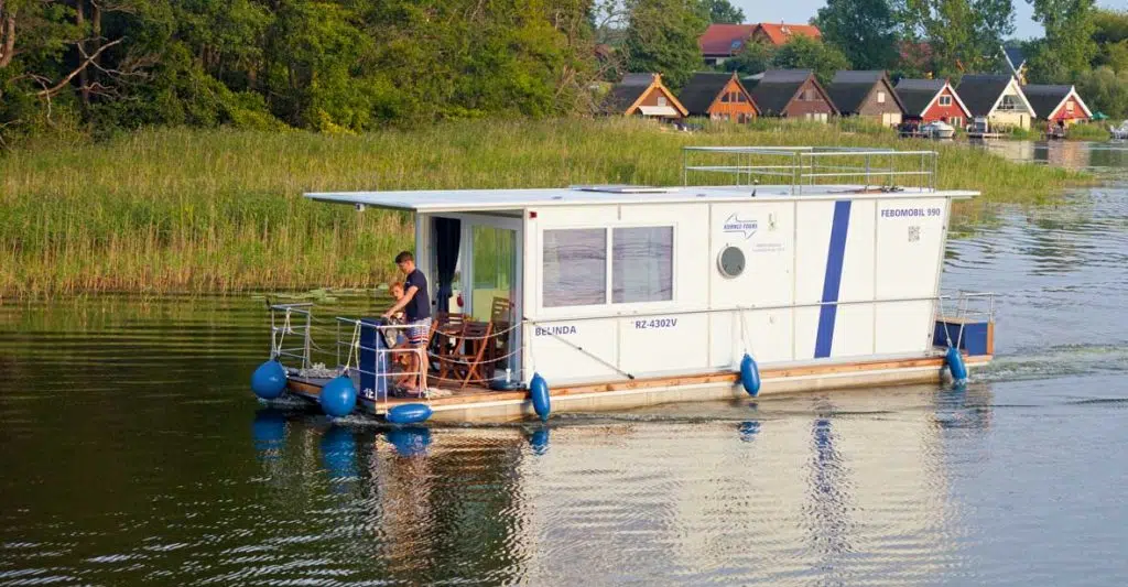 ein Febomobil fährt durch einen Kanal, im Hintergrund hübsche bunte Ferienhäuser