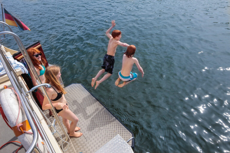 Zwei Personen springen von der Badeplattform einer Kormoran ins wasser