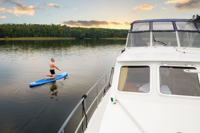 Blick vom Vorschiff der Pedro zum Fahrerstand, man sieht außerdem einen Mann auf einem SUP nebden dem Boot