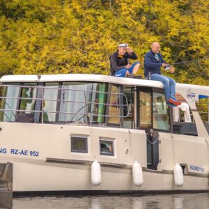 2 Frauen und 2 Männer an Deck der Aquino im Herbst, eine Person angelt