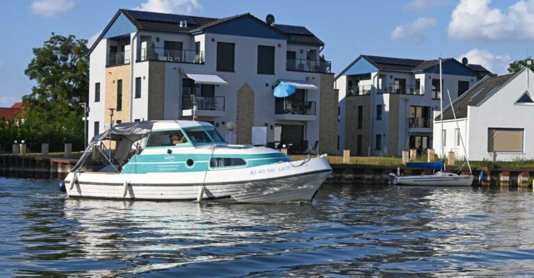 das Boot Bellus fährt durch den Kanal in das Hafenbecken einer Marina