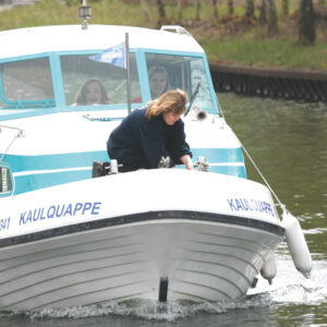 ein Boot fährt durch einen Kanal, an Deck sind 3 Frauen