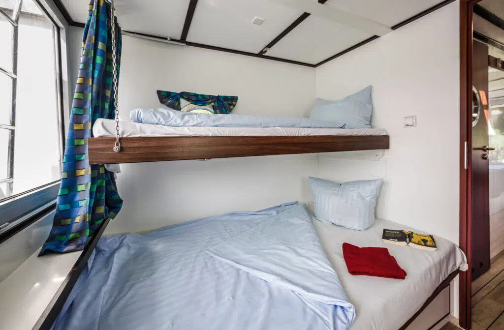 Eine Kabine mit Doppelstockbett. Das untere Bett ist ein Doppelbett, das obere ein Einzelbett.