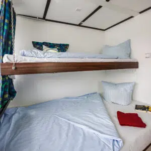 Eine Kabine mit Doppelstockbett. Das untere Bett ist ein Doppelbett, das obere ein Einzelbett.