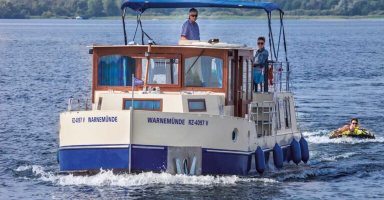 Ein Paar auf einer Kormoran 1150. Hinter der Kormoran hängt eine Person auf einer Tube, einem aufblasbaren Wasserschlitten.