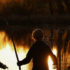 Drei Kinder spielen an einem Fluss bei Sonnenuntergang