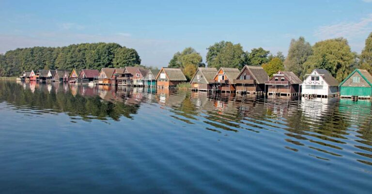 Eine Reihe bunter Bootshäuser an der Müritz.