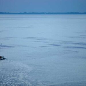 Luftaufnahme der Müritz bei Abend. Ein kleines Boot fährt über das Wasser.