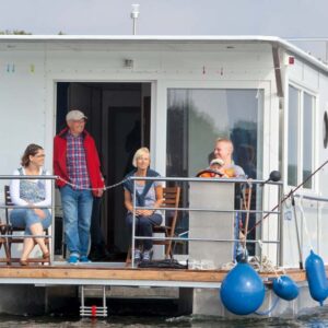 Eine Familie sitzt auf der Veranda des Febo 1180 und genießt ihren Urlaub. Vater und Sohn sitzen gemeinsam am Steuer.