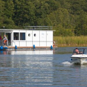 Seitenansicht des Febo1180. Im Vordergrund befindet sich ein Sportboot mit zwei Personen.