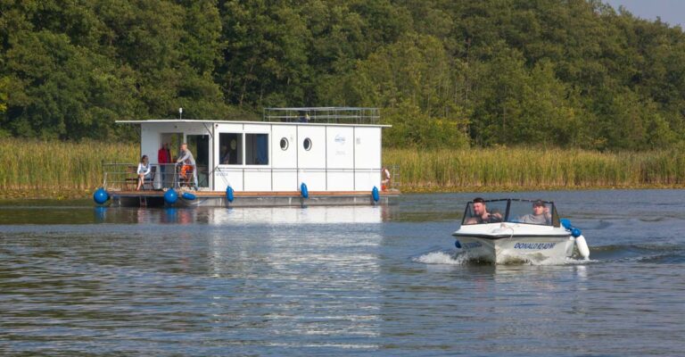 Seitenansicht des Febo1180. Im Vordergrund befindet sich ein Sportboot mit zwei Personen.