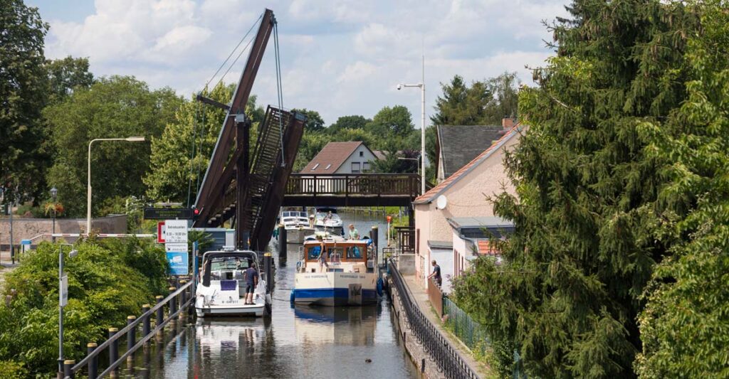 Eine Kormoran passiert eine Klappbrücke.