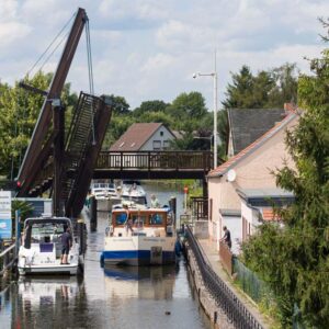 Eine Kormoran passiert eine Klappbrücke.