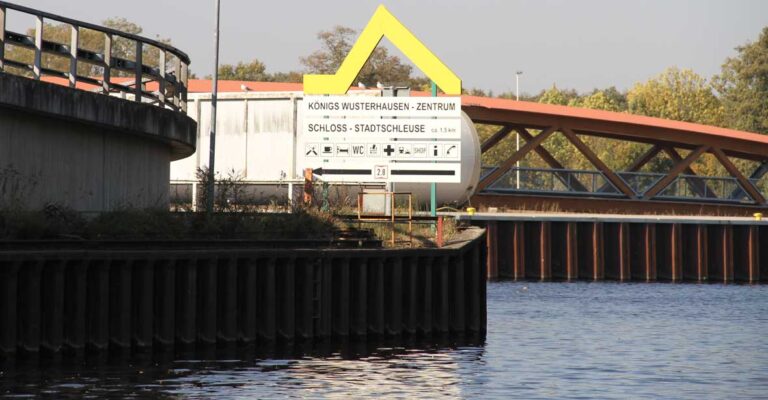 Ein Schild im Kanal zu Königs Wusterhausen mit Richtungsweiser zum Zentrum sowie der Stadtschleuse.