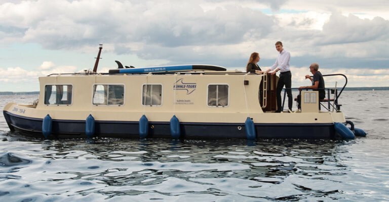 Seitenansicht der Kuinder. Ein blau-beiges, längliches Boot.