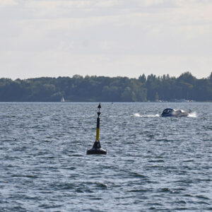 Die Müritz vor Röbel. Man sieht ein kleines Sportboot sowie eine Boje. Im Hintergrund sieht man die Kirche in Röbel.