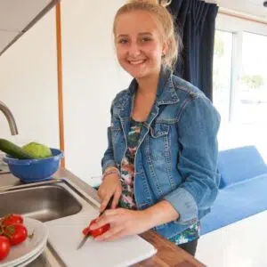 Eine junge Frau steht an der Küchenzeile des Febo720 Cabin und schneidet Tomaten.
