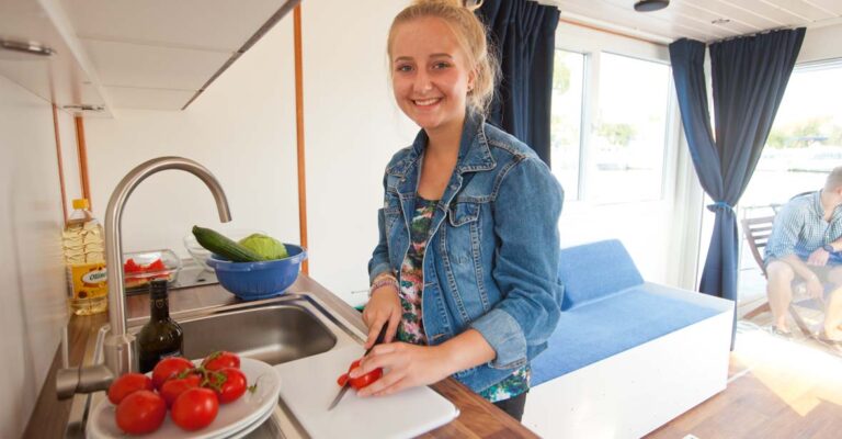 Eine junge Frau steht an der Küchenzeile des Febo720 Cabin und schneidet Tomaten.