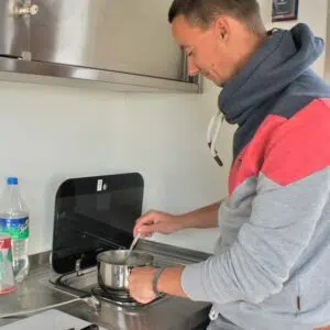 ein man steht an der Küchenzeile des Febo720 open und kocht auf dem Gasherd