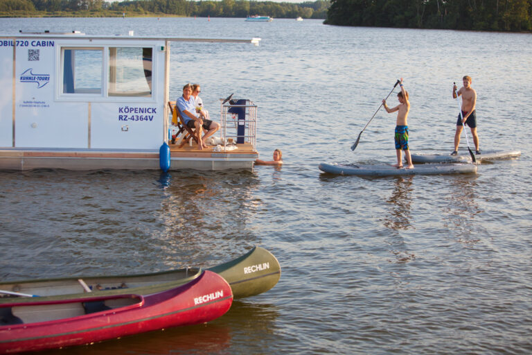 zwei Jungen auf SUPs paddeln zum Febo720 Cabin