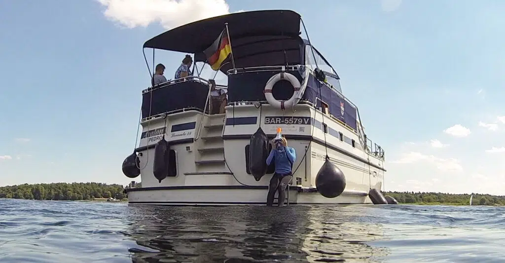 Heckansicht der Pedro Levanto. eine Person sitzt unten auf der Badeplattform und bereit sich aufs Tauchen vor.