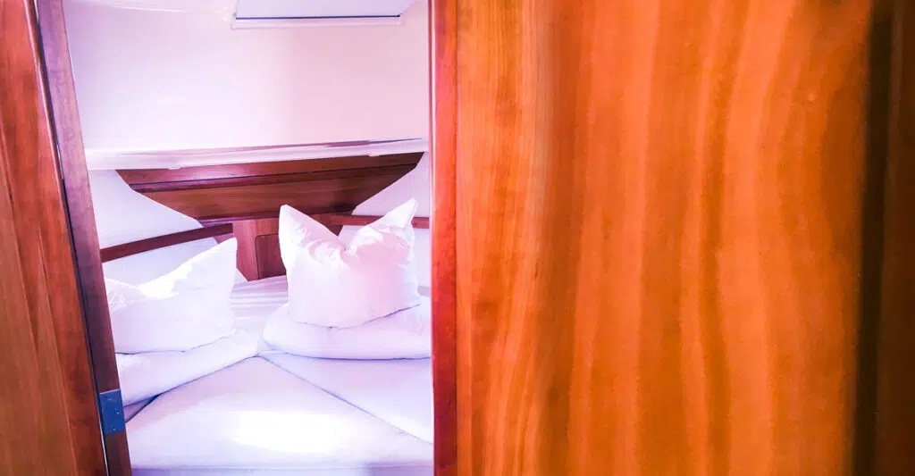 Ein Blick in die Bugkabine der Delphia Escape. Ein Doppelbett mit Kissen und decken in weißen Bezügen.