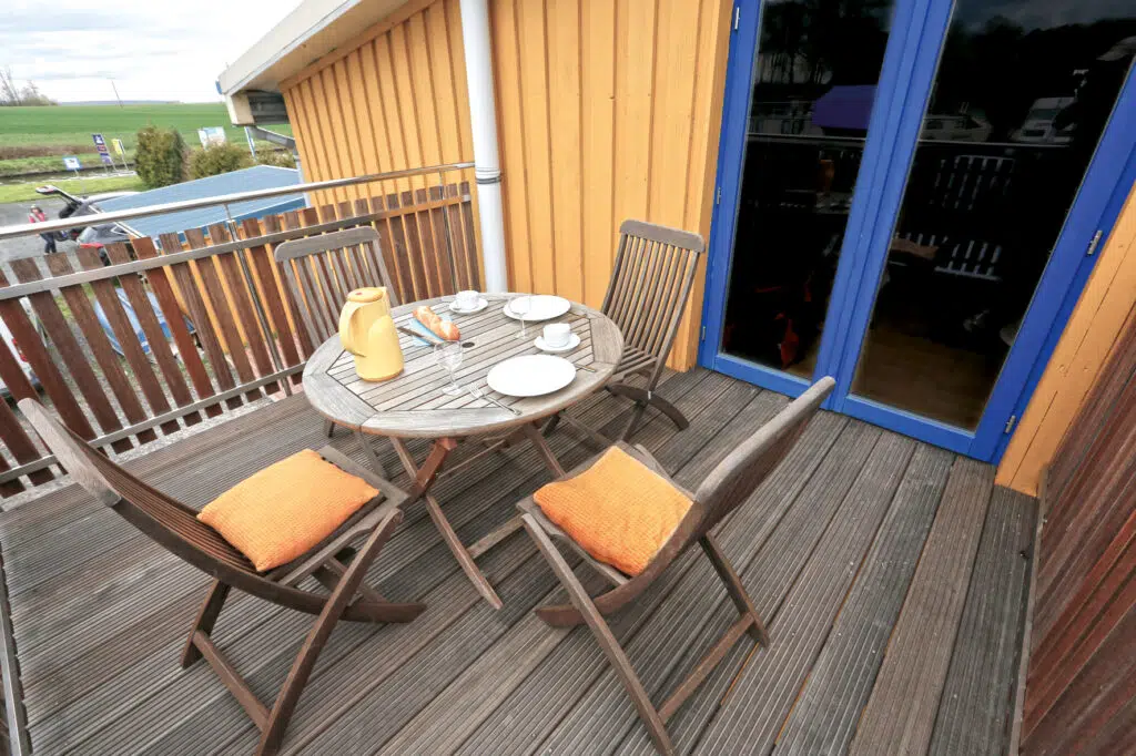 Ein Balkon mit einem kleinen runden Tisch und vier Stühlen.