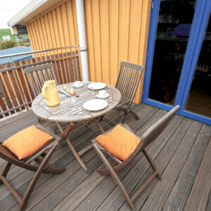 Ein Balkon mit einem kleinen runden Tisch und vier Stühlen.