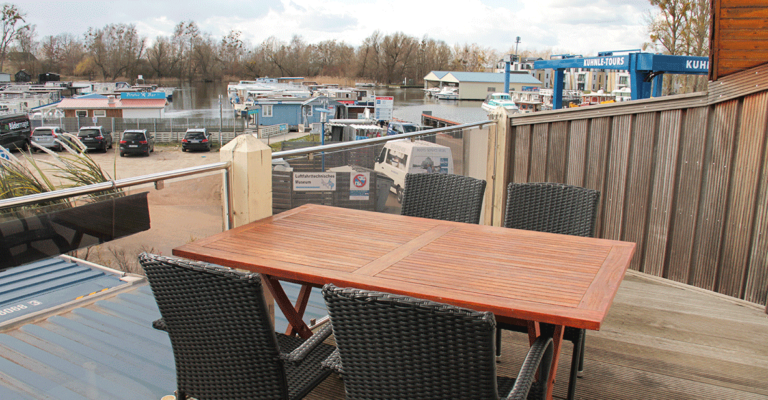 Großer Balkon mit Tisch und Blick auf den Hafen.