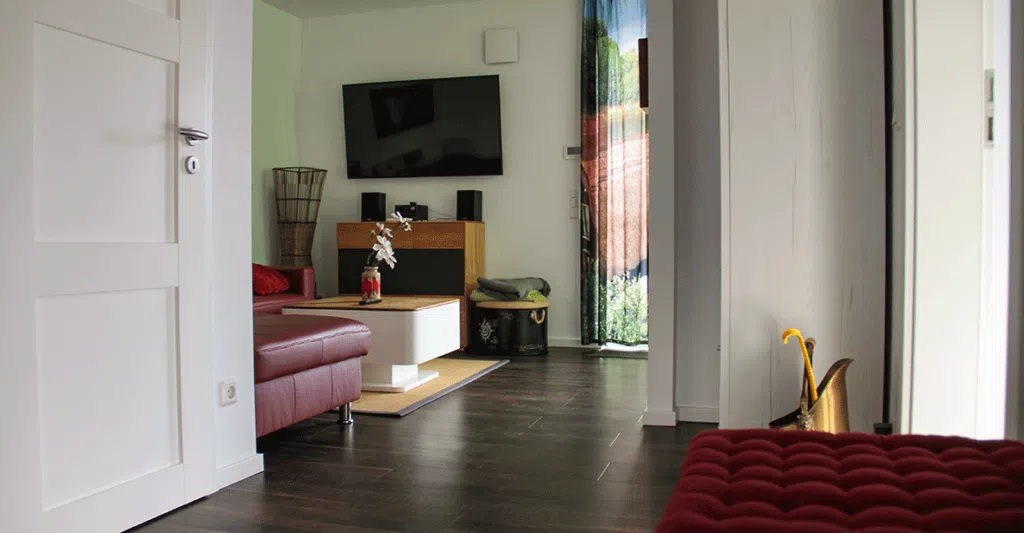 Blick auf das Wohnzimmer einer Ferienwohnung mit Fernseher mit Stereoanlage, Couch und Couchtisch