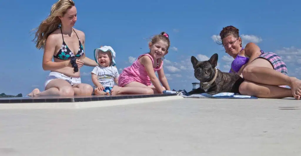 an Deck eines Hausbootes sitzen zwei kleine Kinder und ein Hund
