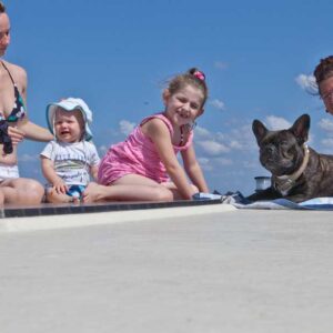 an Deck eines Hausbootes sitzen zwei kleine Kinder und ein Hund